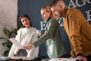 deux femmes et un homme observe une fiche debout face à une table.